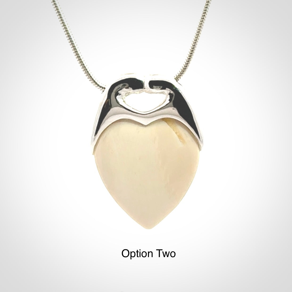This picture shows a pendant that we have carved in a combination of sterling silver and woolly mammoth. It shows a symbolic kiss, with two heads coming together and both embracing a woolly mammoth heart. The necklace is a sterling silver chain.