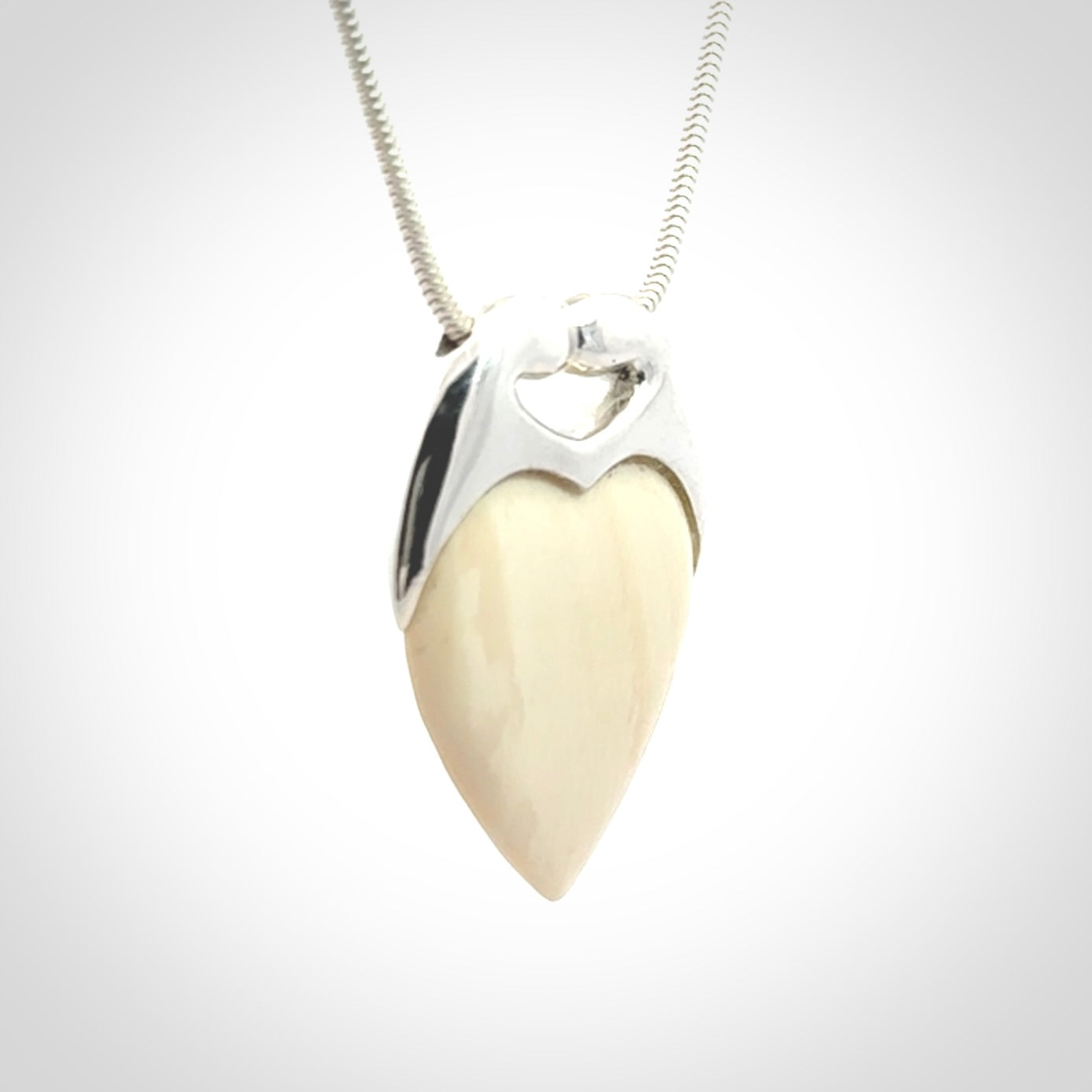 This picture shows a pendant that we have carved in a combination of sterling silver and woolly mammoth. It shows a symbolic kiss, with two heads coming together and both embracing a woolly mammoth heart. The necklace is a sterling silver chain.