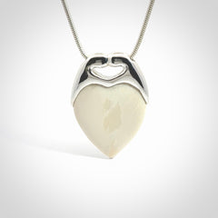This picture shows a pendant that we have carved in a combination of sterling silver and woolly mammoth. It shows a symbolic kiss, with two heads coming together and both embracing a woolly mammoth heart. The necklace is a sterling silver chain.