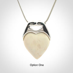 This picture shows a pendant that we have carved in a combination of sterling silver and woolly mammoth. It shows a symbolic kiss, with two heads coming together and both embracing a woolly mammoth heart. The necklace is a sterling silver chain.