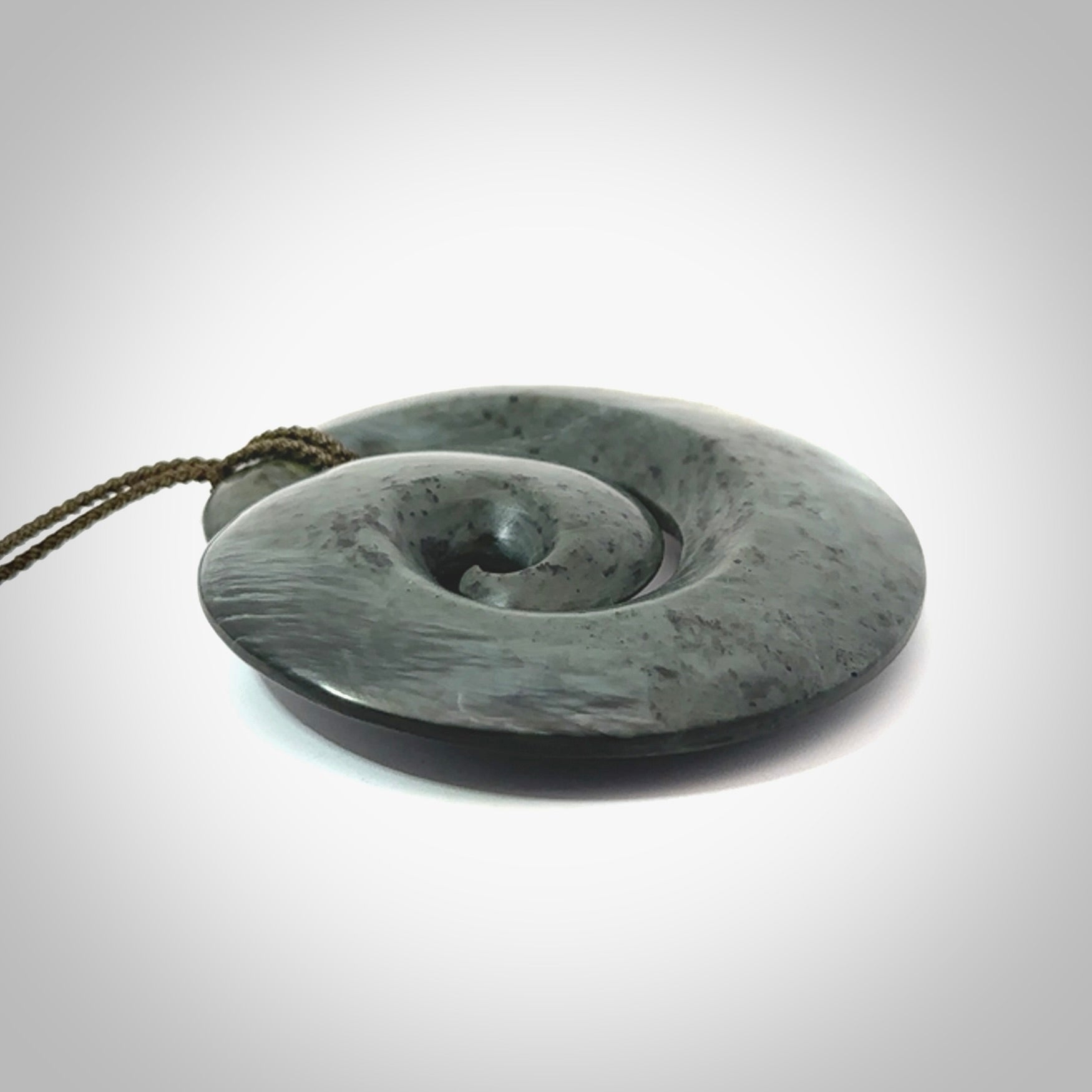 This pendant is a large sized koru necklace carved from a blue/grey piece of New Zealand Jade. Kyohei Noguchi carved this piece for us so the workmanship is outstanding. Handmade in New Zealand, a beautiful piece of jade jewellery.