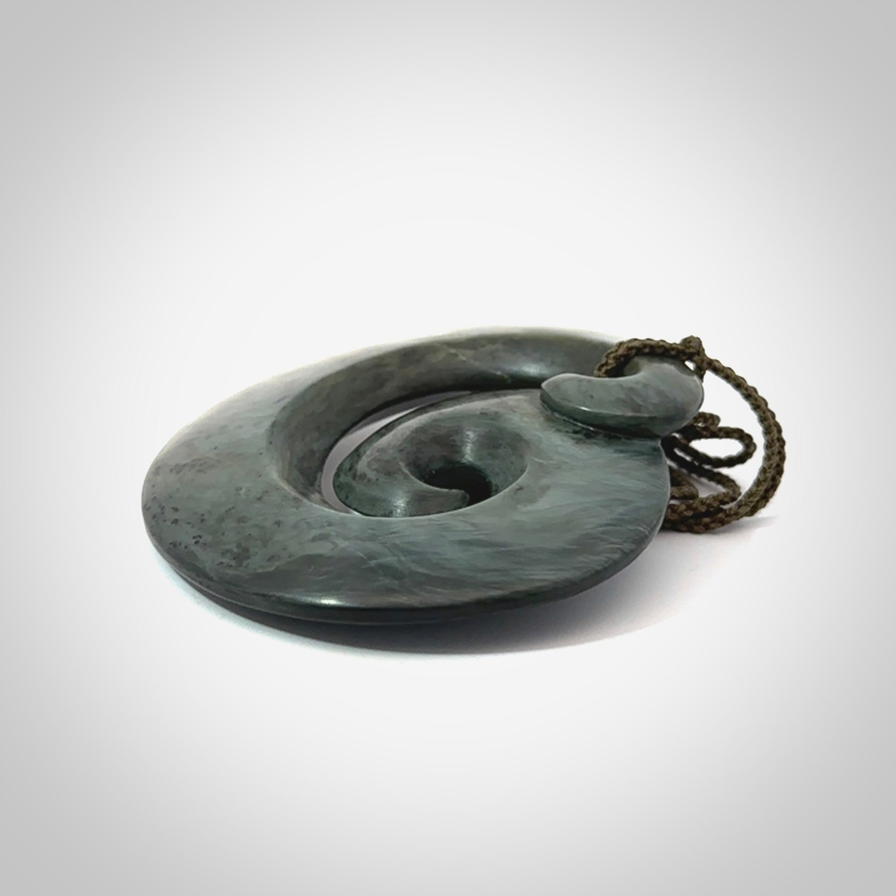 This pendant is a large sized koru necklace carved from a blue/grey piece of New Zealand Jade. Kyohei Noguchi carved this piece for us so the workmanship is outstanding. Handmade in New Zealand, a beautiful piece of jade jewellery.