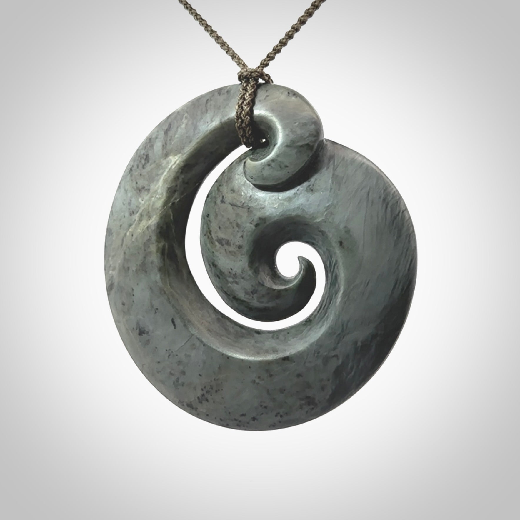 This pendant is a large sized koru necklace carved from a blue/grey piece of New Zealand Jade. Kyohei Noguchi carved this piece for us so the workmanship is outstanding. Handmade in New Zealand, a beautiful piece of jade jewellery.