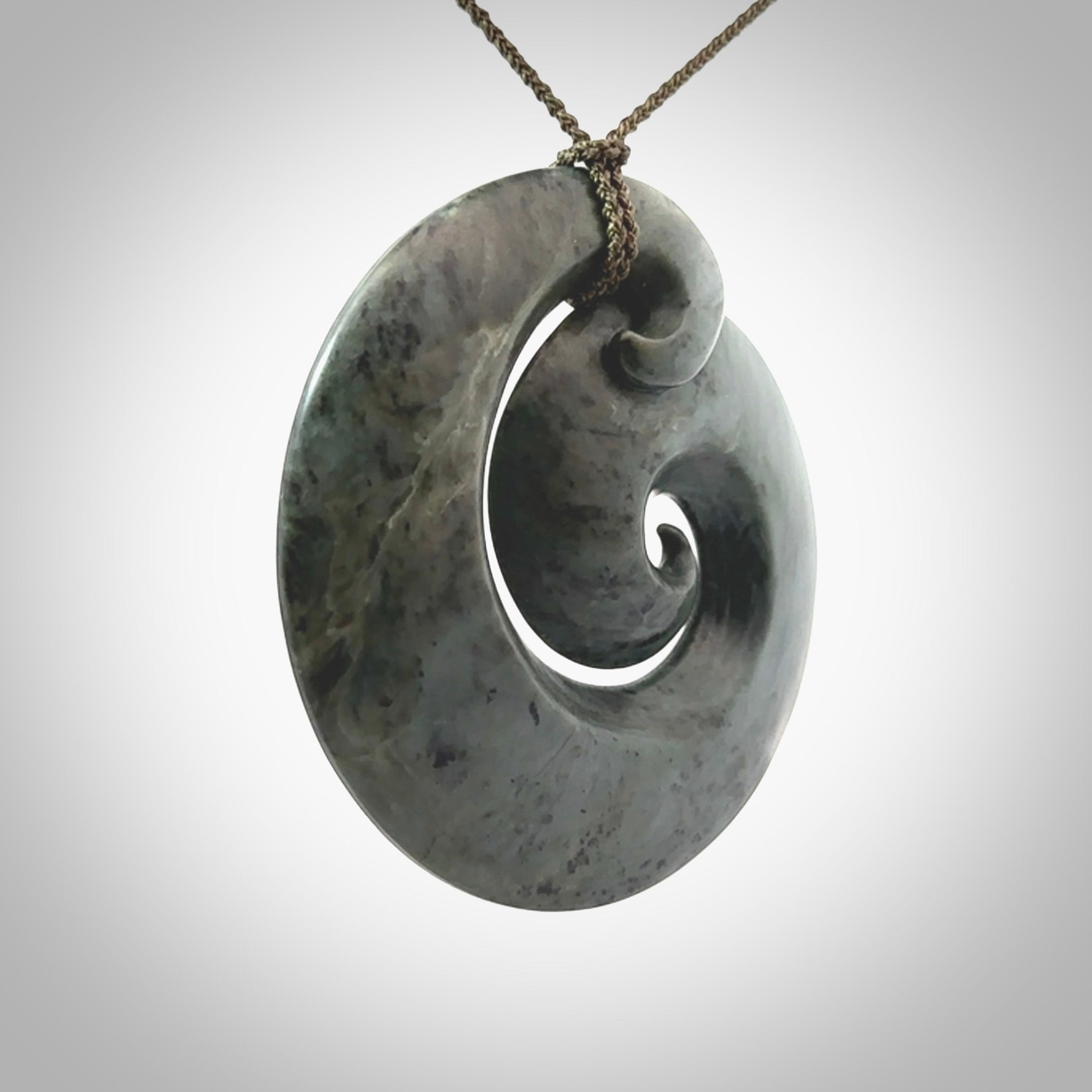 This pendant is a large sized koru necklace carved from a blue/grey piece of New Zealand Jade. Kyohei Noguchi carved this piece for us so the workmanship is outstanding. Handmade in New Zealand, a beautiful piece of jade jewellery.