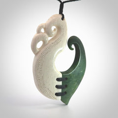 This photo shows a wonderful hand carved New Zealand jade and Whale Bone Manaia with hook pendant. The hook is suspended on a black four plait cord that is length adjustable.