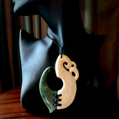 This photo shows a wonderful hand carved New Zealand jade and Whale Bone Manaia with hook pendant. The hook is suspended on a black four plait cord that is length adjustable.
