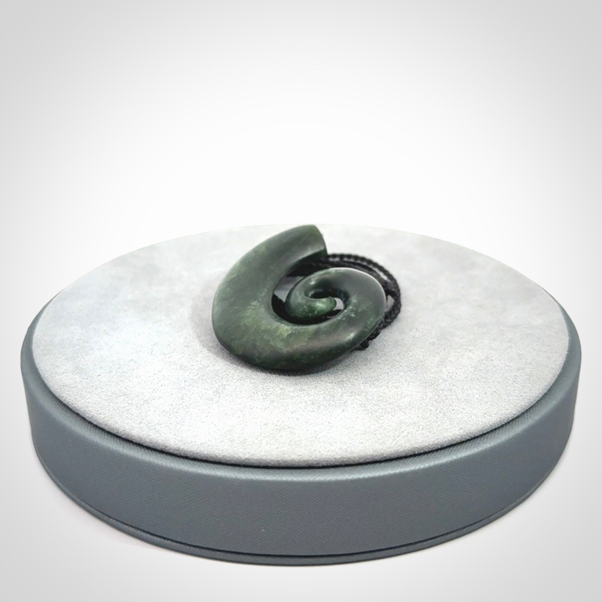 This picture shows a koru pendant, hand carved from New Zealand jade. We will provide this with an adjustable black plaited cord. This has been hand carved by Kyohei Noguchi. One only pendant, shipped to you with express courier.