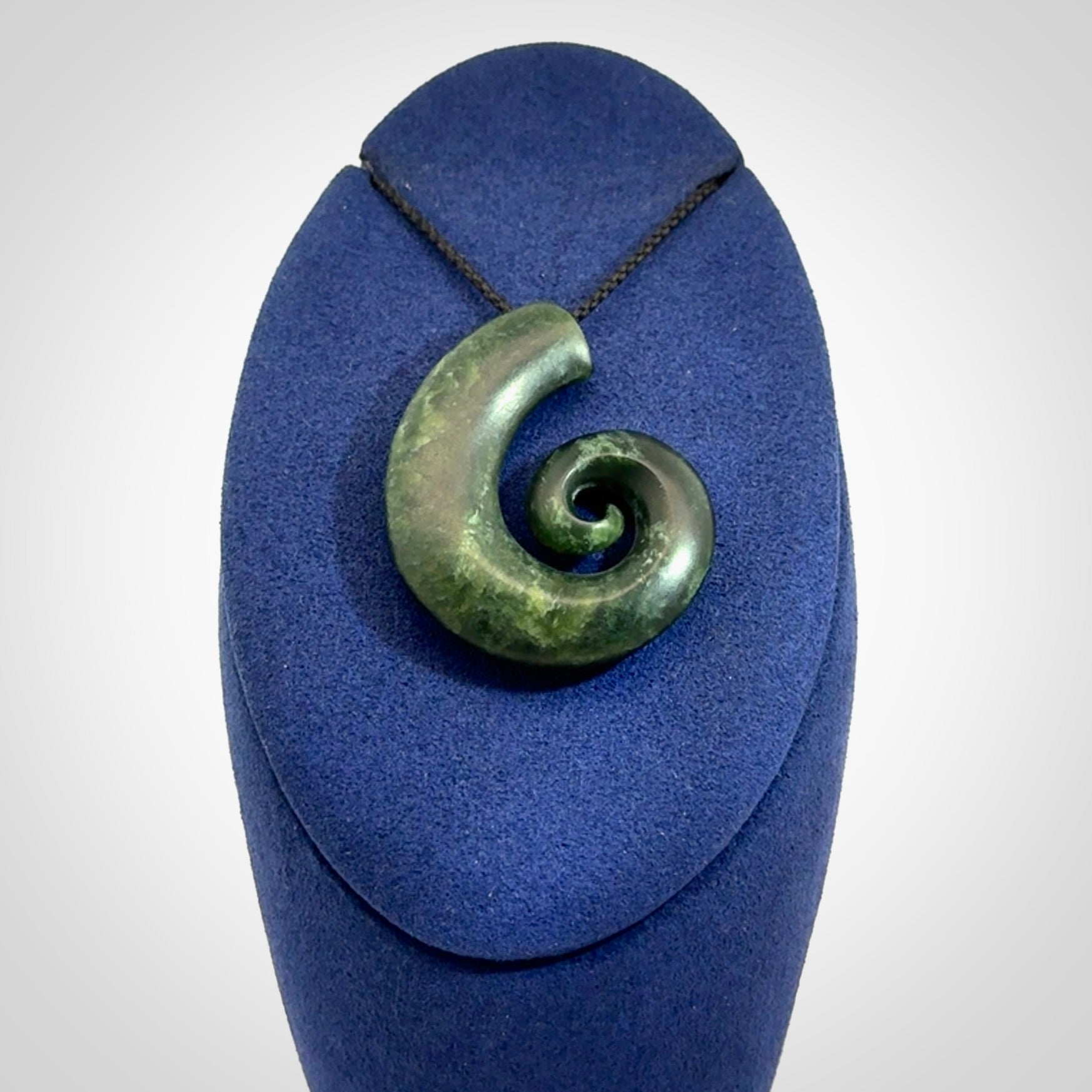 This picture shows a koru pendant, hand carved from New Zealand jade. We will provide this with an adjustable black plaited cord. This has been hand carved by Kyohei Noguchi. One only pendant, shipped to you with express courier.