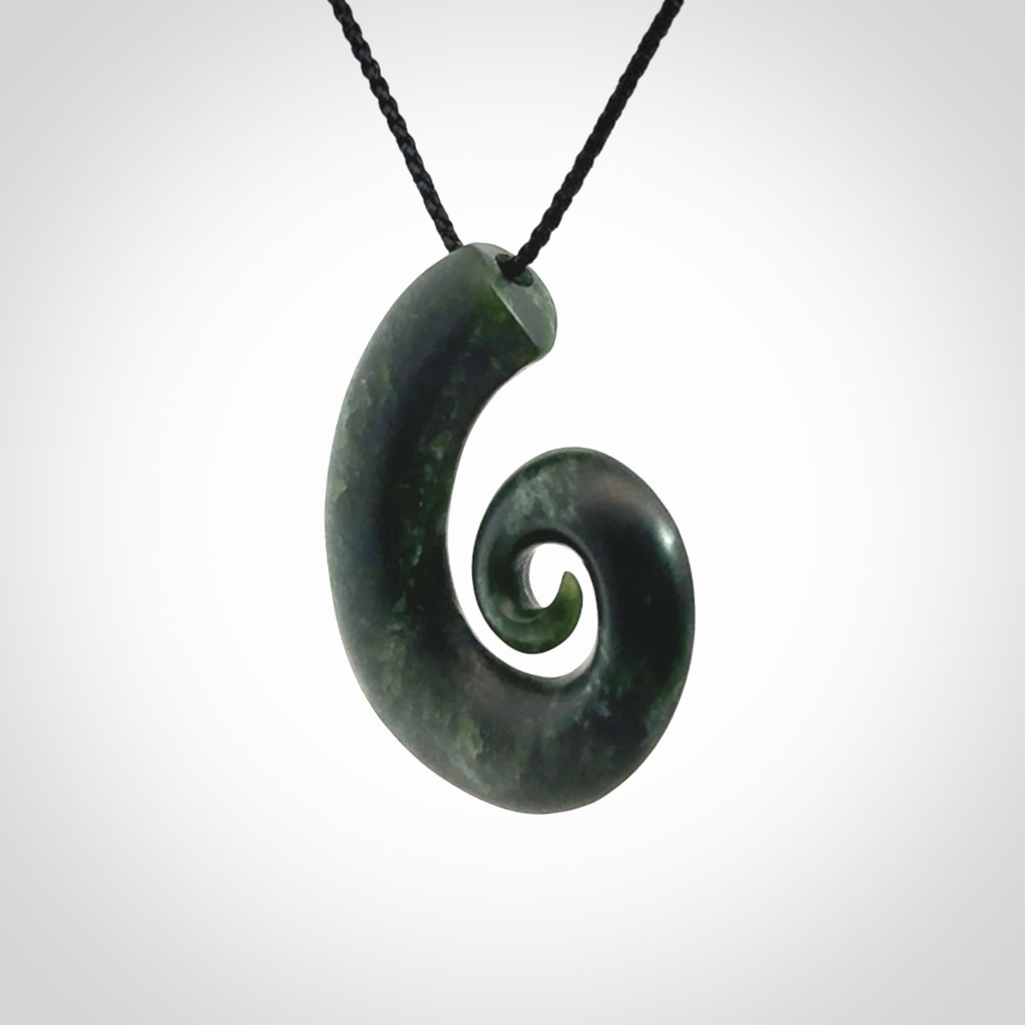 This picture shows a koru pendant, hand carved from New Zealand jade. We will provide this with an adjustable black plaited cord. This has been hand carved by Kyohei Noguchi. One only pendant, shipped to you with express courier.
