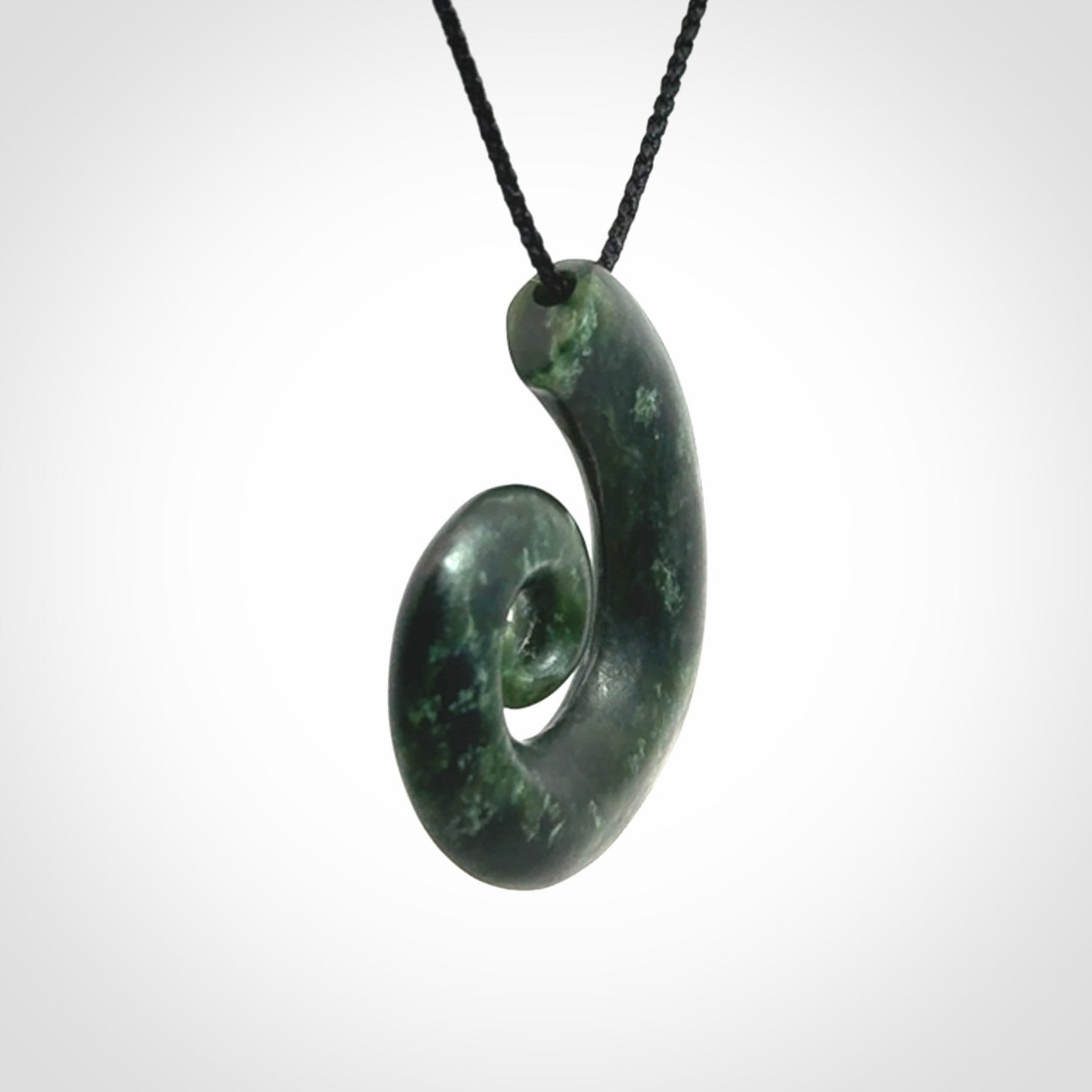 This picture shows a koru pendant, hand carved from New Zealand jade. We will provide this with an adjustable black plaited cord. This has been hand carved by Kyohei Noguchi. One only pendant, shipped to you with express courier.