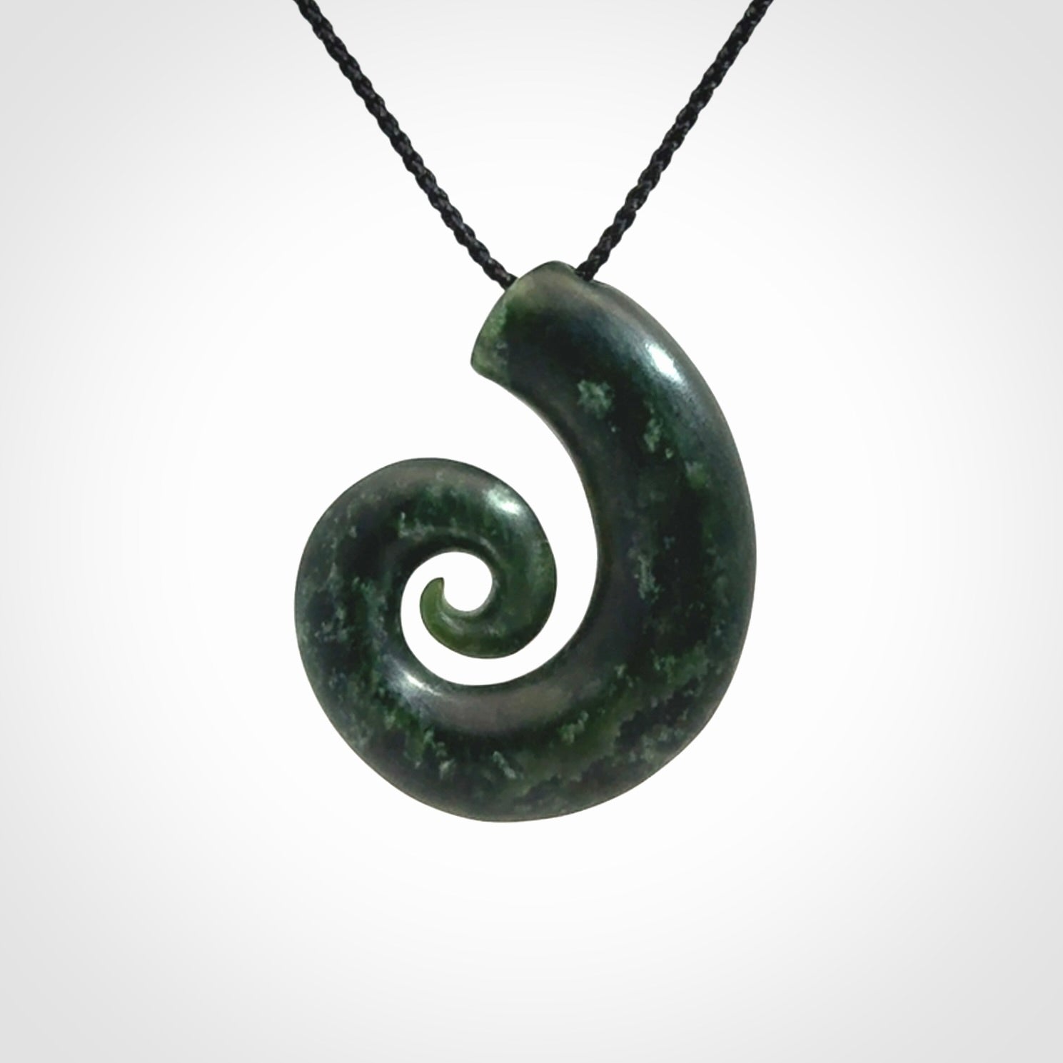 This picture shows a koru pendant, hand carved from New Zealand jade. We will provide this with an adjustable black plaited cord. This has been hand carved by Kyohei Noguchi. One only pendant, shipped to you with express courier.