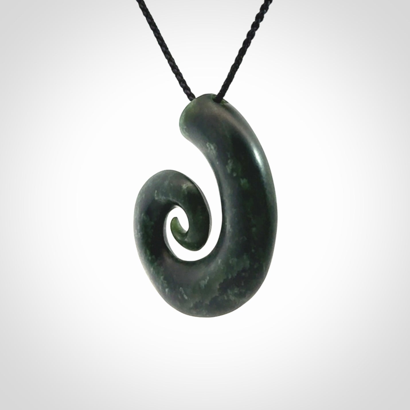 This picture shows a koru pendant, hand carved from New Zealand jade. We will provide this with an adjustable black plaited cord. This has been hand carved by Kyohei Noguchi. One only pendant, shipped to you with express courier.