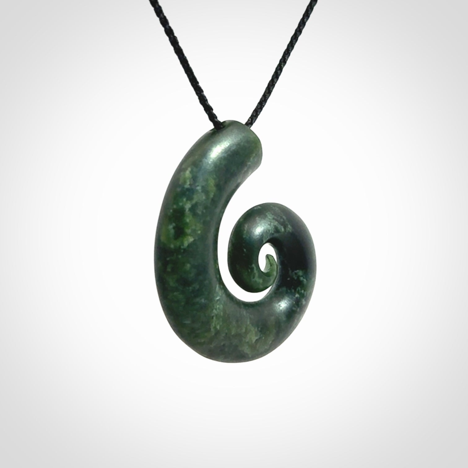 This picture shows a koru pendant, hand carved from New Zealand jade. We will provide this with an adjustable black plaited cord. This has been hand carved by Kyohei Noguchi. One only pendant, shipped to you with express courier.