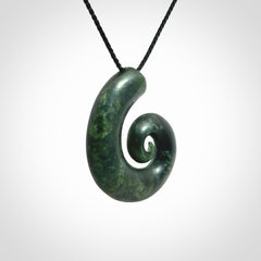This picture shows a koru pendant, hand carved from New Zealand jade. We will provide this with an adjustable black plaited cord. This has been hand carved by Kyohei Noguchi. One only pendant, shipped to you with express courier.