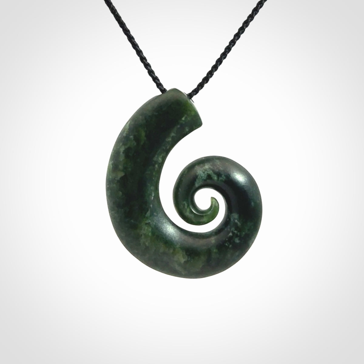 This picture shows a koru pendant, hand carved from New Zealand jade. We will provide this with an adjustable black plaited cord. This has been hand carved by Kyohei Noguchi. One only pendant, shipped to you with express courier.
