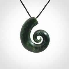This picture shows a koru pendant, hand carved from New Zealand jade. We will provide this with an adjustable black plaited cord. This has been hand carved by Kyohei Noguchi. One only pendant, shipped to you with express courier.