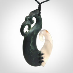 This photo shows a wonderful hand carved New Zealand jade and Japanese Agate Manaia with hook pendant. The hook is suspended on a black four plait cord that is length adjustable.