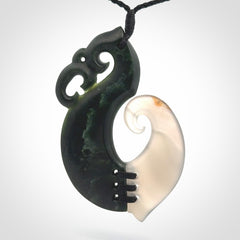 This photo shows a wonderful hand carved New Zealand jade and Japanese Agate Manaia with hook pendant. The hook is suspended on a black four plait cord that is length adjustable.