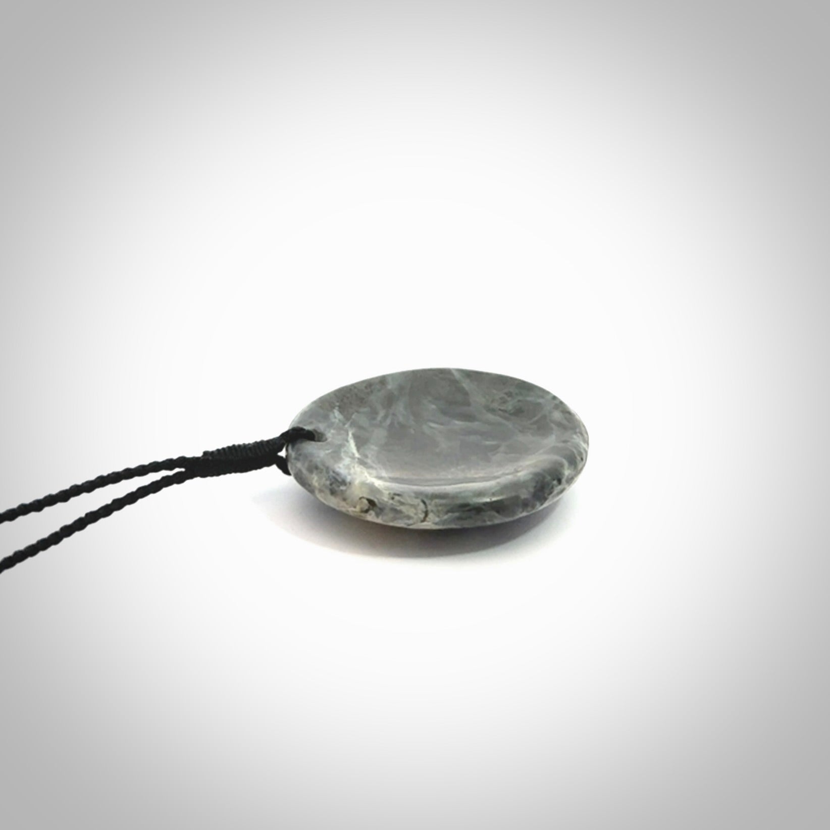 This cupped disc pendant, is carved from a very striking New Zealand Nelson jade.