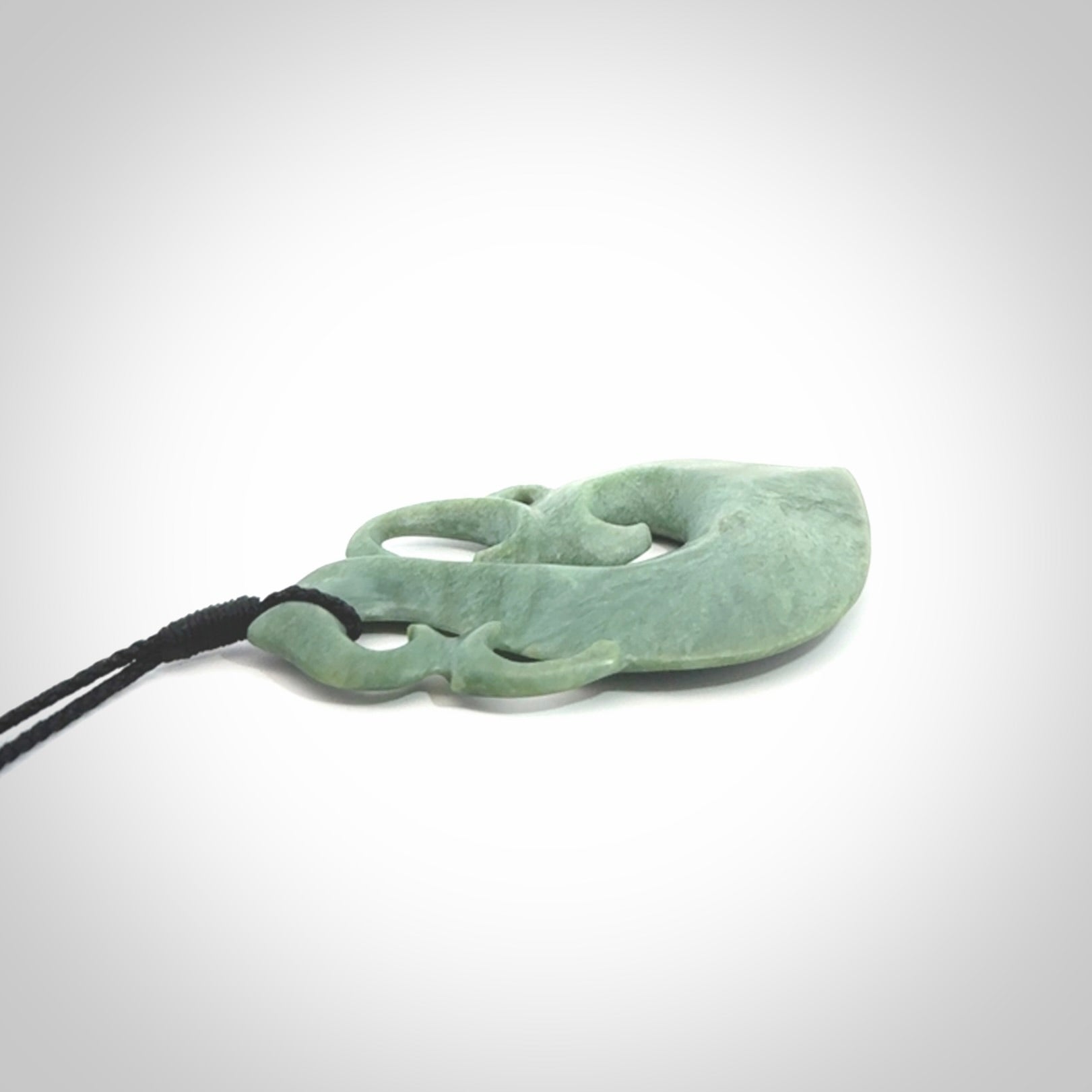 This picture shows a contemporary manaia with hook pendant carved for us by Kyohei Noguchi. It is a light green colour in traditional manaia design. We have plaited a cord in black and made it length adjustable. This is a very beautiful piece of art to wear.