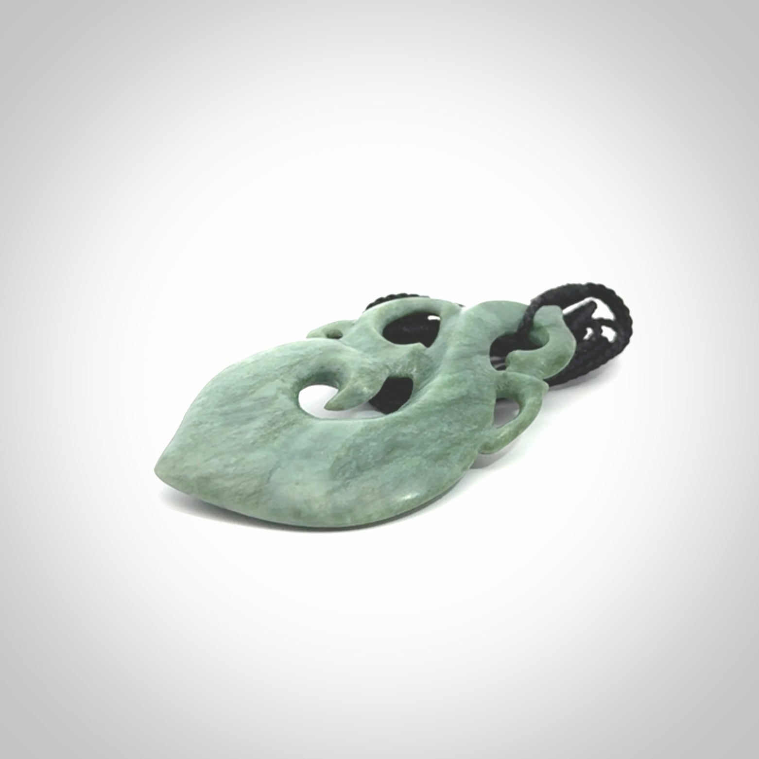 This picture shows a contemporary manaia with hook pendant carved for us by Kyohei Noguchi. It is a light green colour in traditional manaia design. We have plaited a cord in black and made it length adjustable. This is a very beautiful piece of art to wear.