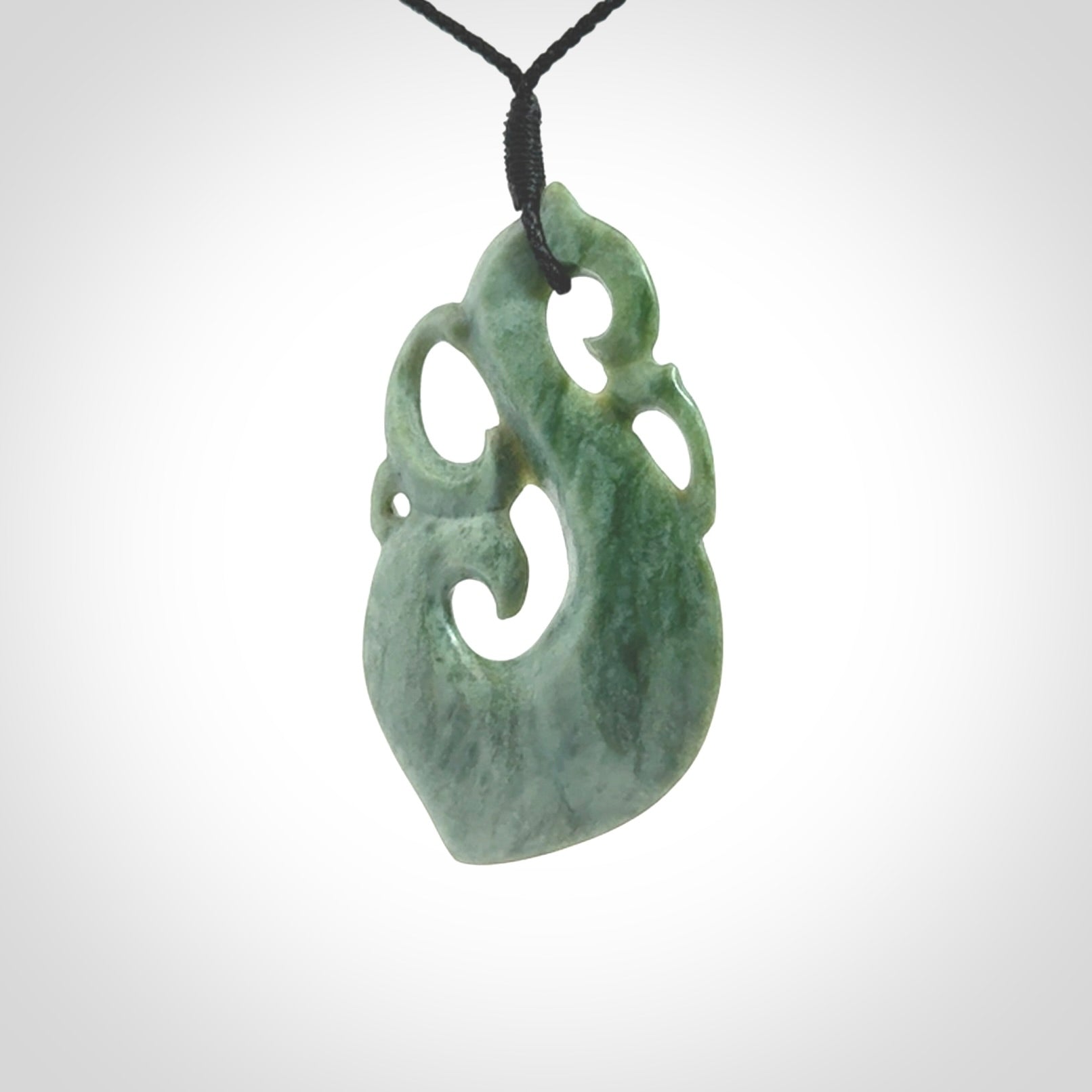This picture shows a contemporary manaia with hook pendant carved for us by Kyohei Noguchi. It is a light green colour in traditional manaia design. We have plaited a cord in black and made it length adjustable. This is a very beautiful piece of art to wear.