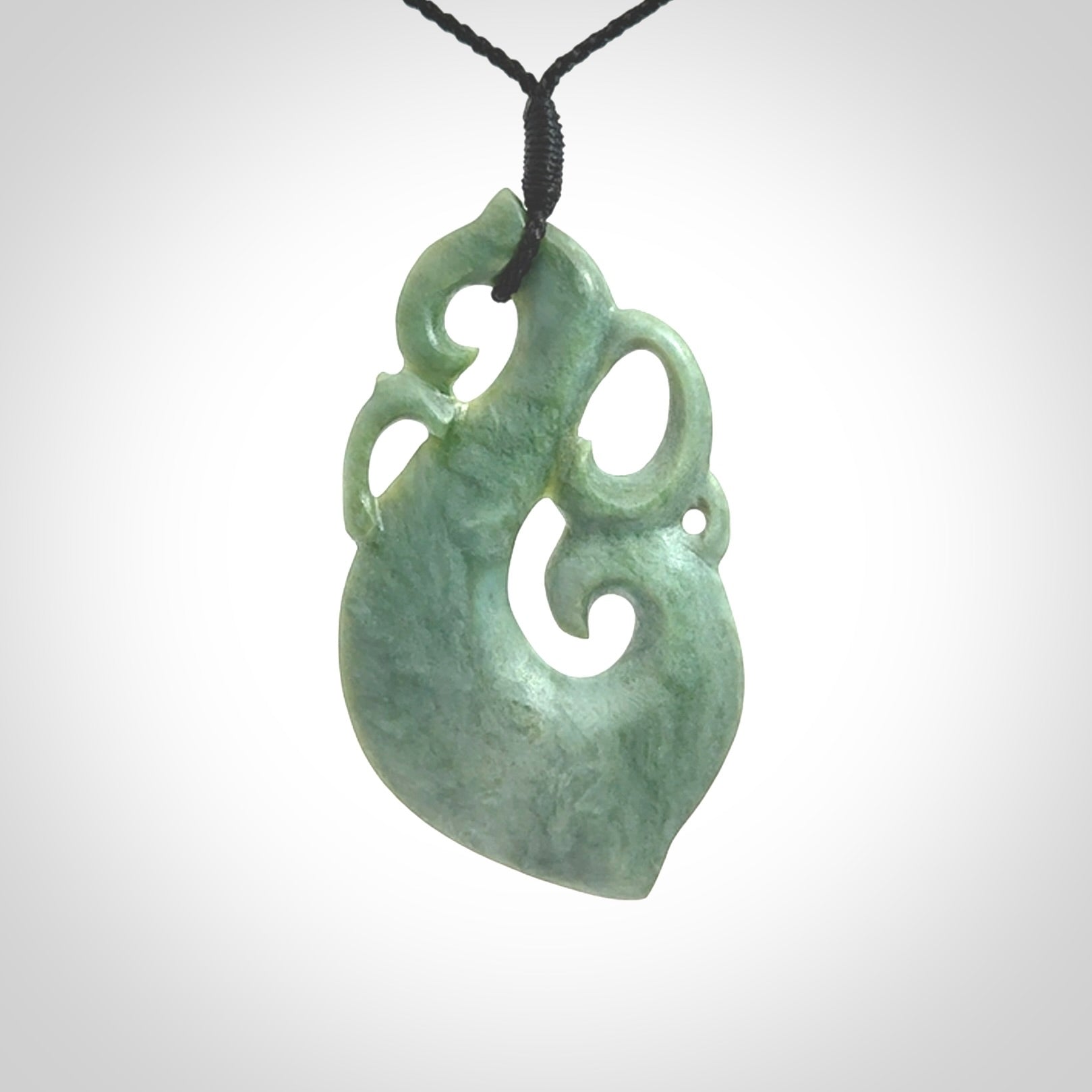 This picture shows a contemporary manaia with hook pendant carved for us by Kyohei Noguchi. It is a light green colour in traditional manaia design. We have plaited a cord in black and made it length adjustable. This is a very beautiful piece of art to wear.