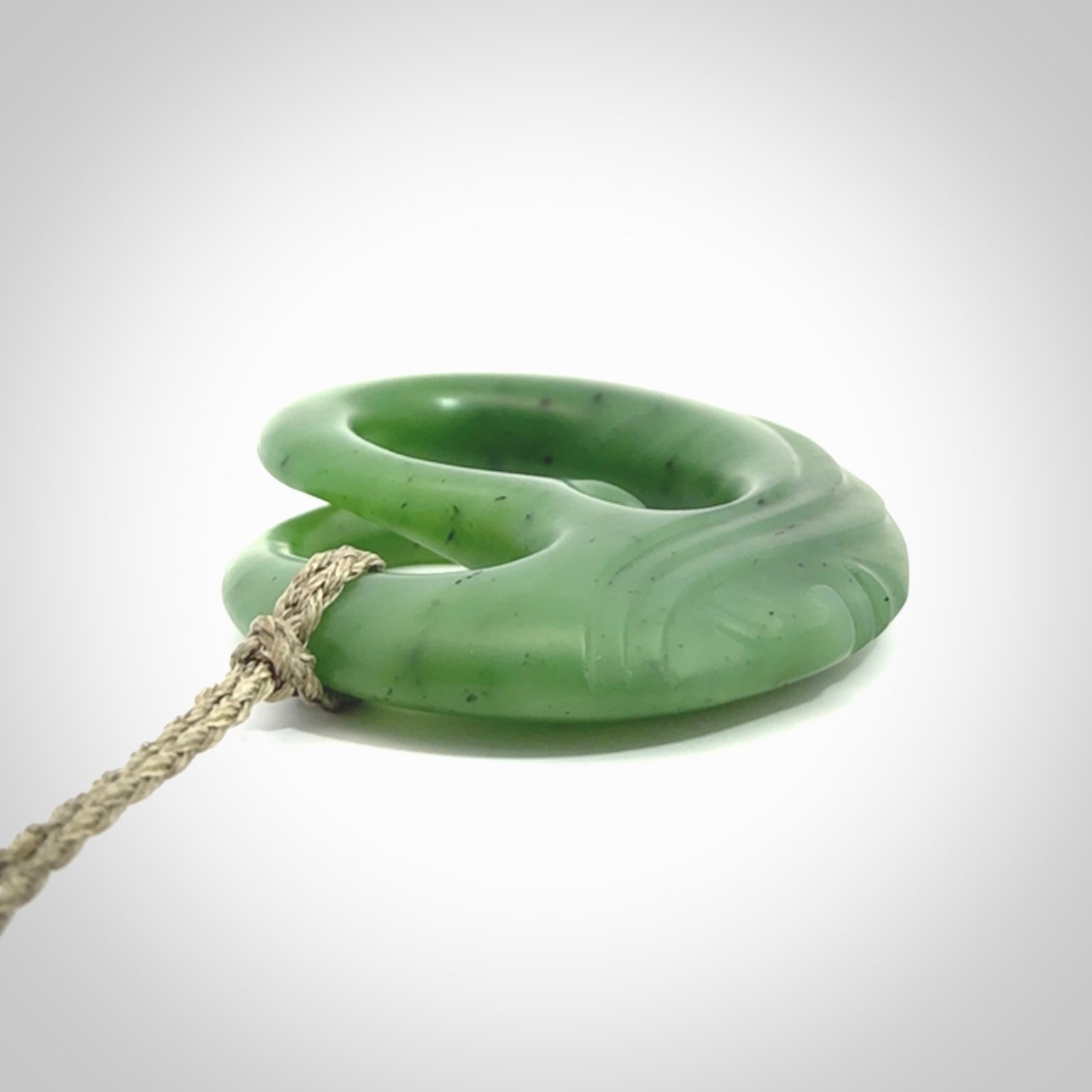 A hand carved complex face pendant from Siberian Jade. The cord is 4-plait khaki and is adjustable.