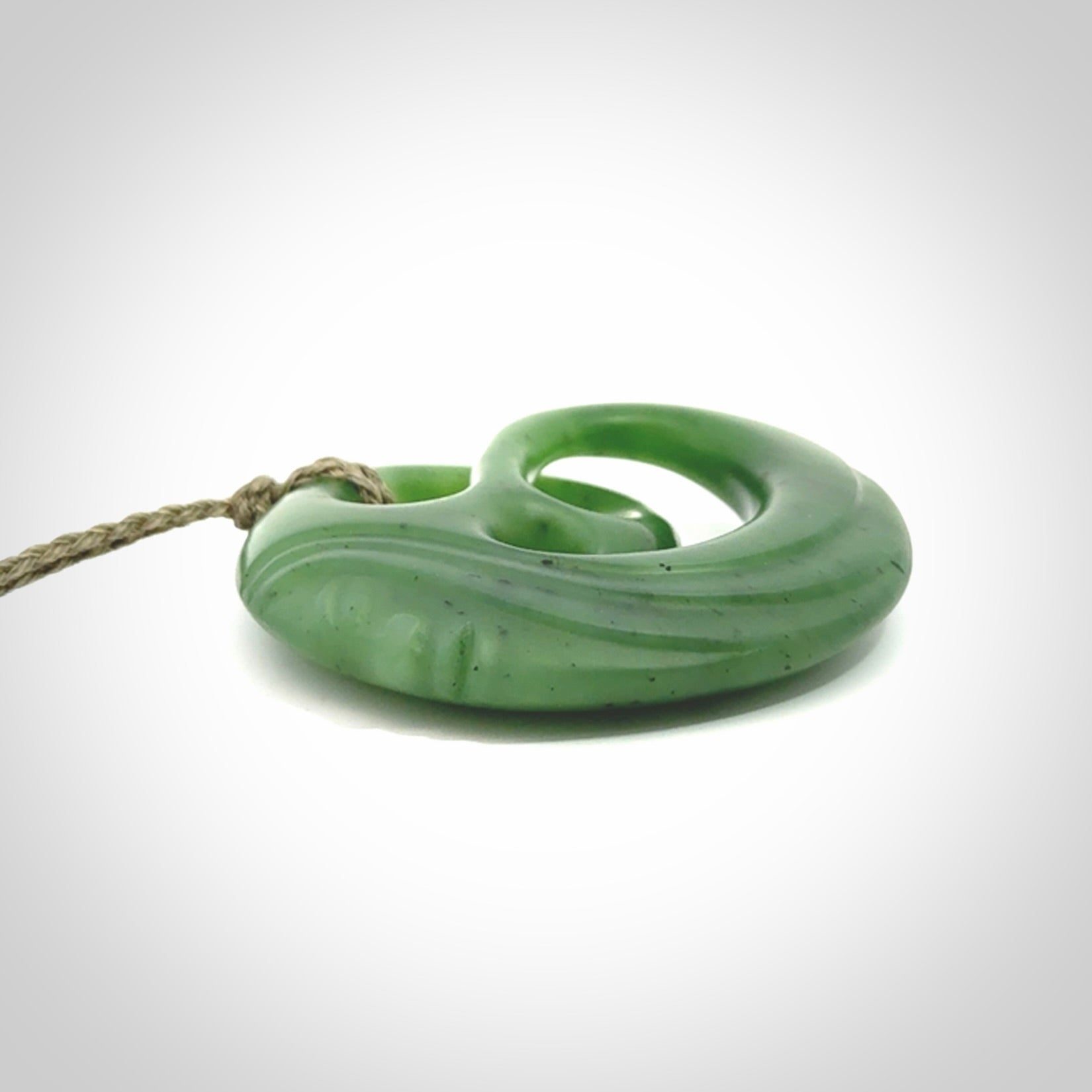 A hand carved complex face pendant from Siberian Jade. The cord is 4-plait khaki and is adjustable.