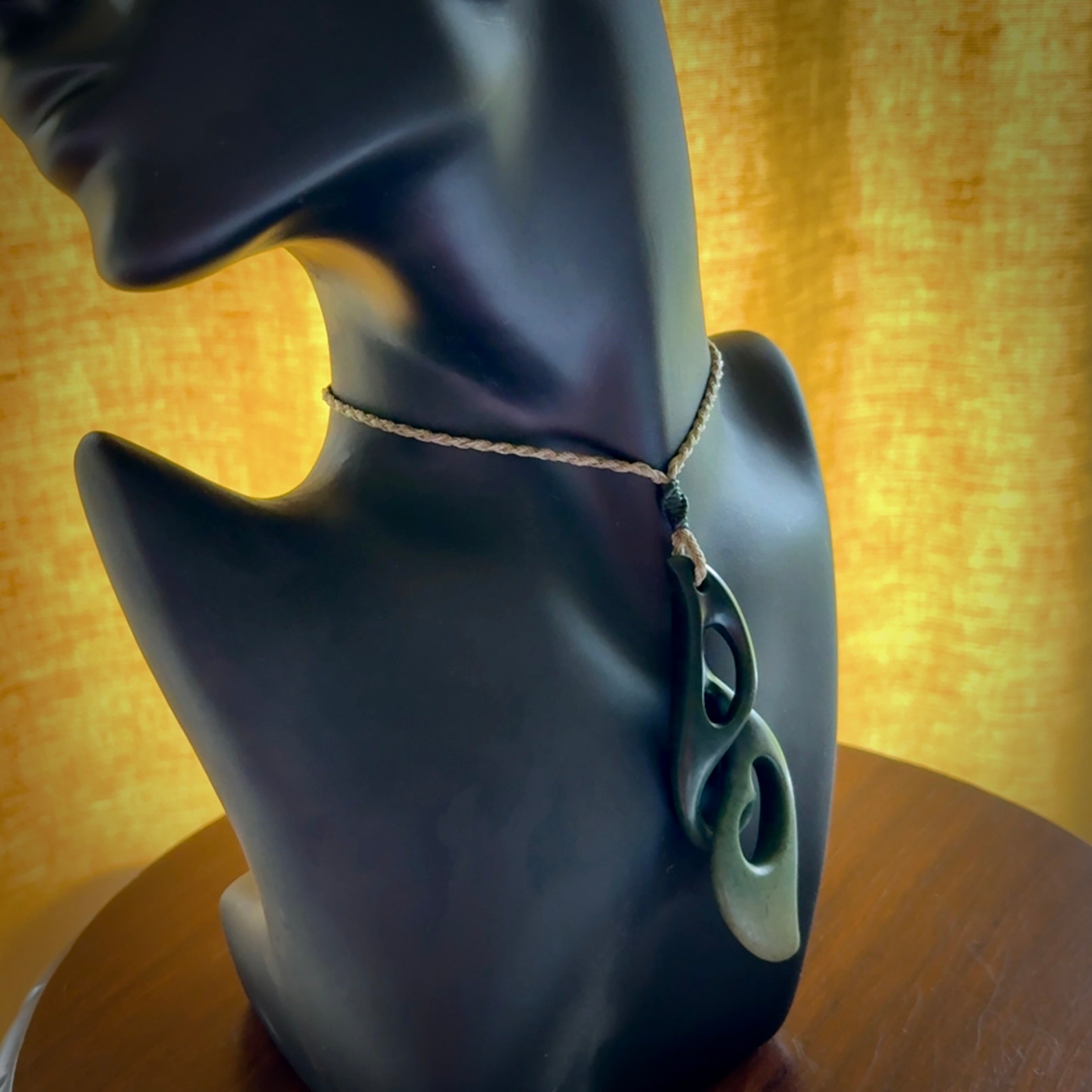 A hand carved twist pendant from New Zealand Jade. The cord is a khaki green colour and is adjustable.