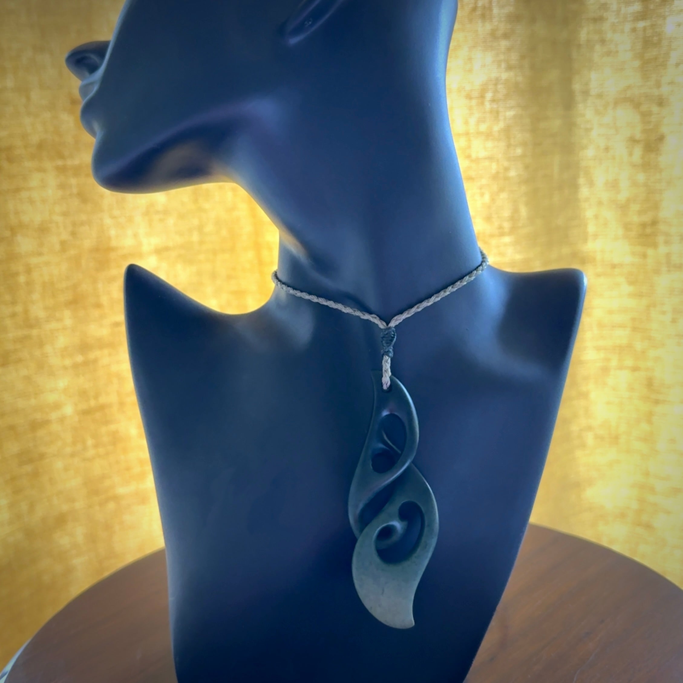 A hand carved twist pendant from New Zealand Jade. The cord is a khaki green colour and is adjustable.