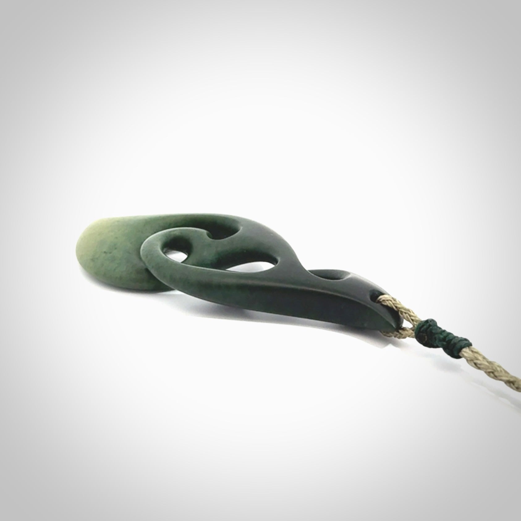 A hand carved twist pendant from New Zealand Jade. The cord is a khaki green colour and is adjustable.