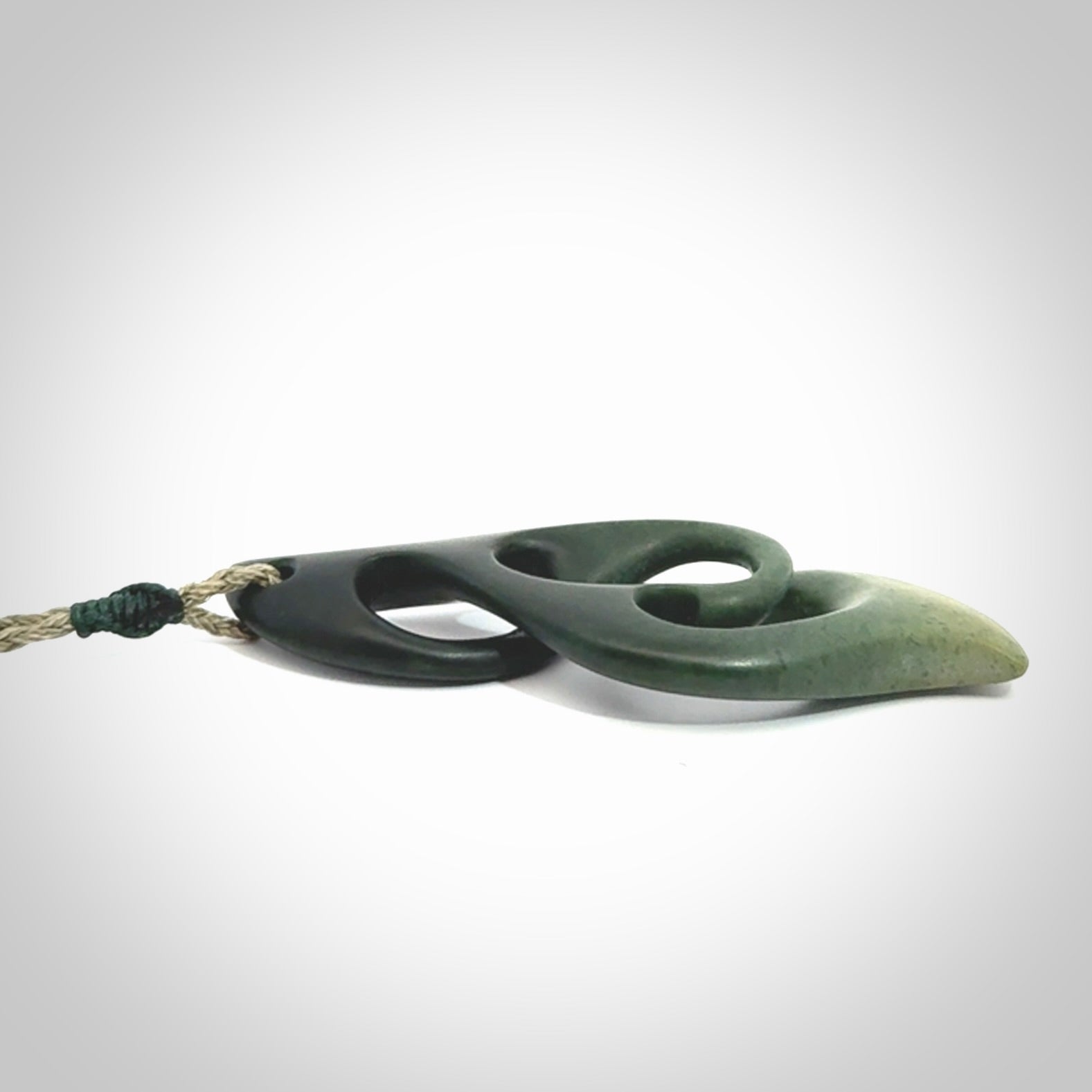 A hand carved twist pendant from New Zealand Jade. The cord is a khaki green colour and is adjustable.