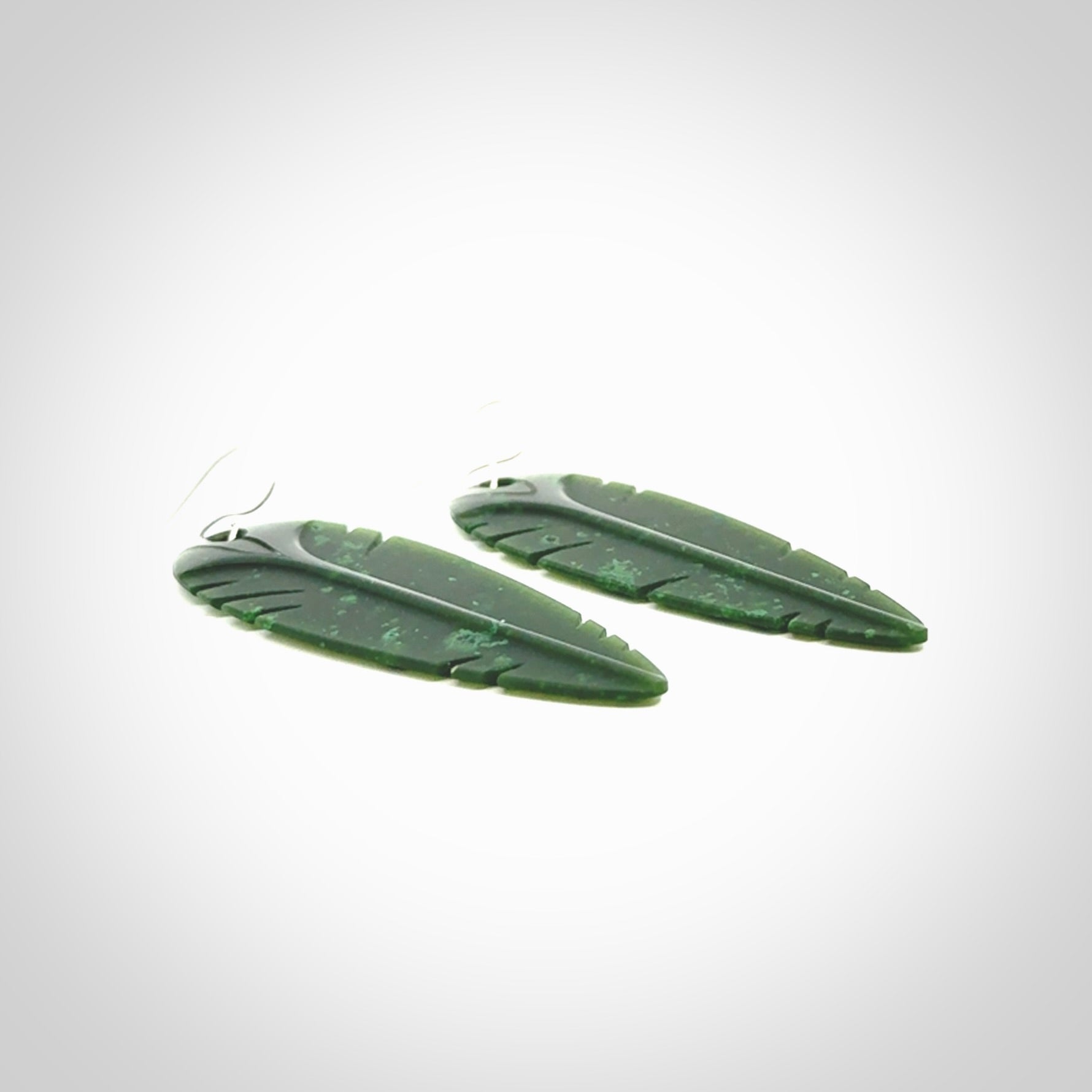This picture shows British Columbian jade kaka feather earrings with sterling silver hooks. Hand made unique and contemporary feather earrings by Kerry Thompson. Hand carved here in New Zealand from British Columbian Jade. One pair only.