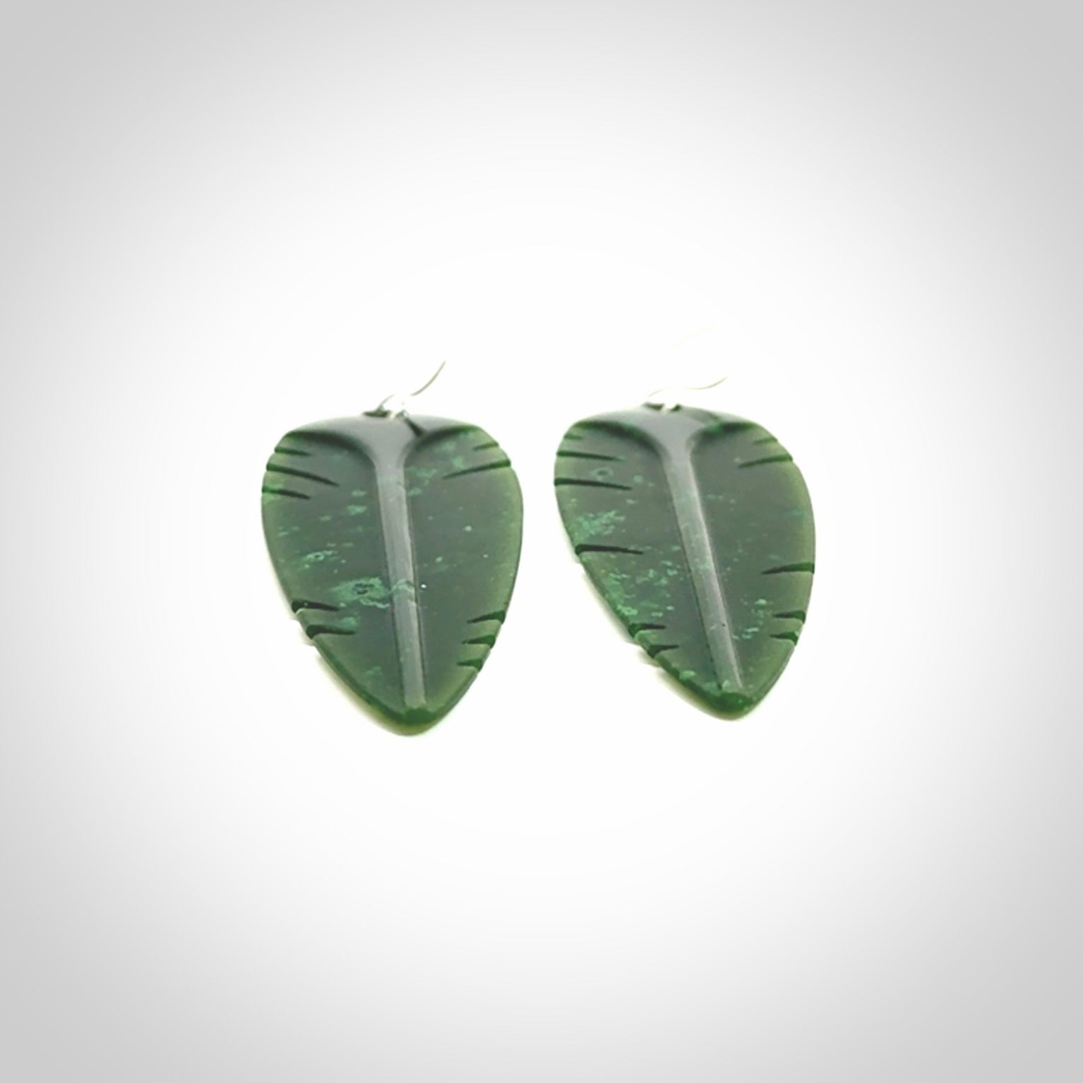 This picture shows British Columbian jade kaka feather earrings with sterling silver hooks. Hand made unique and contemporary feather earrings by Kerry Thompson. Hand carved here in New Zealand from British Columbian Jade. One pair only.