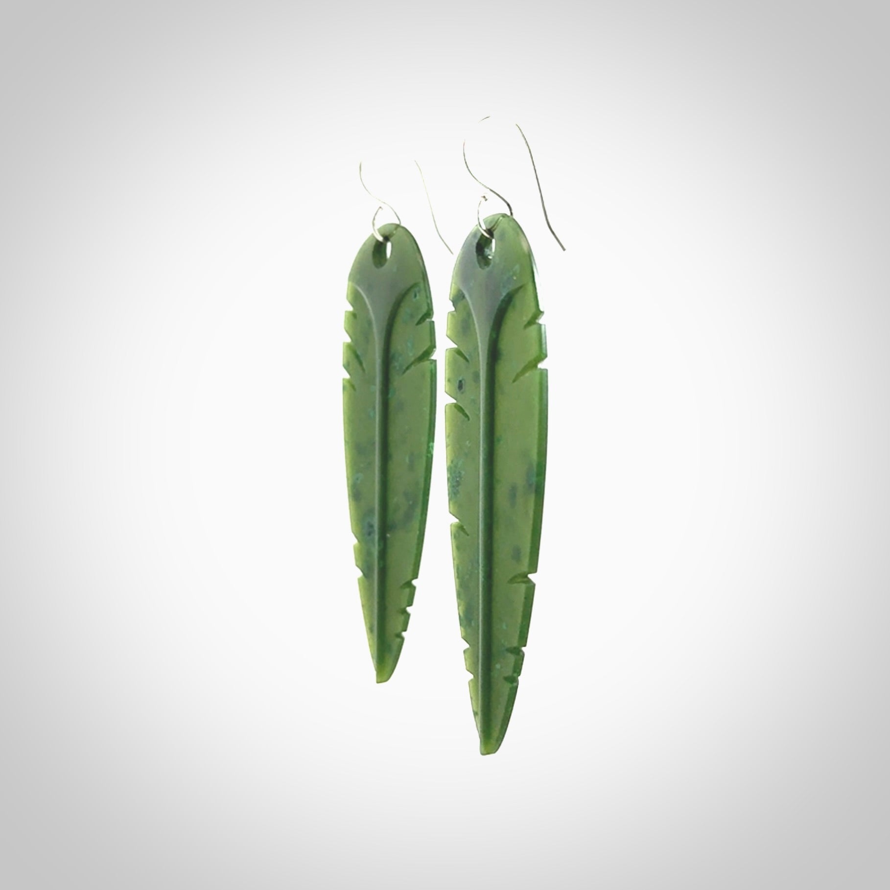 This picture shows British Columbian jade kaka feather earrings with sterling silver hooks. Hand made unique and contemporary feather earrings by Kerry Thompson. Hand carved here in New Zealand from British Columbian Jade. One pair only.