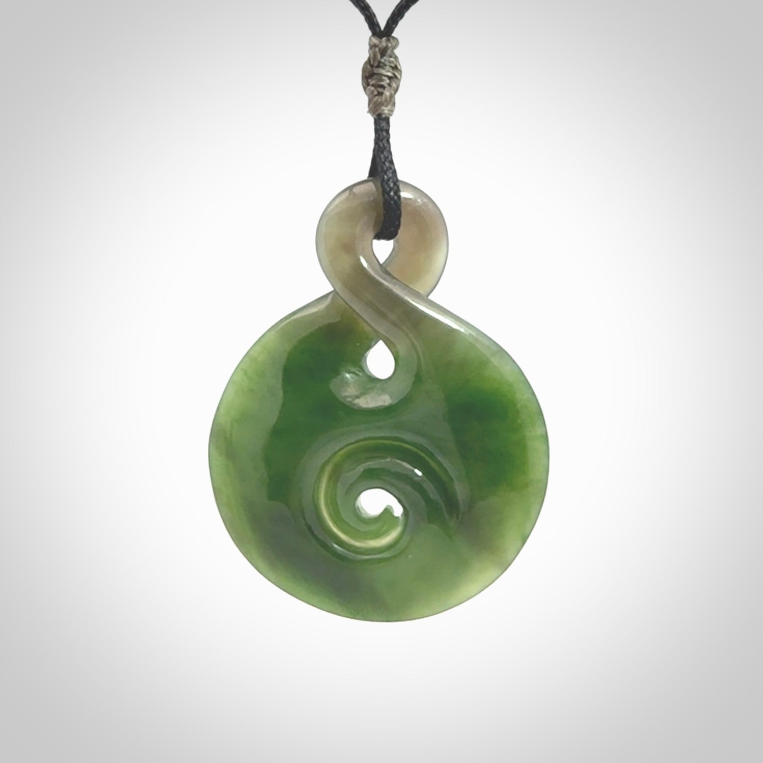 Hand carved New Zealand Jade Twist with Koru heart pendant. Unique Jade jewellery online for sale. Hand made Jade Twist with Koru, provided on adjustable cords and packaged in a woven kete pouch.