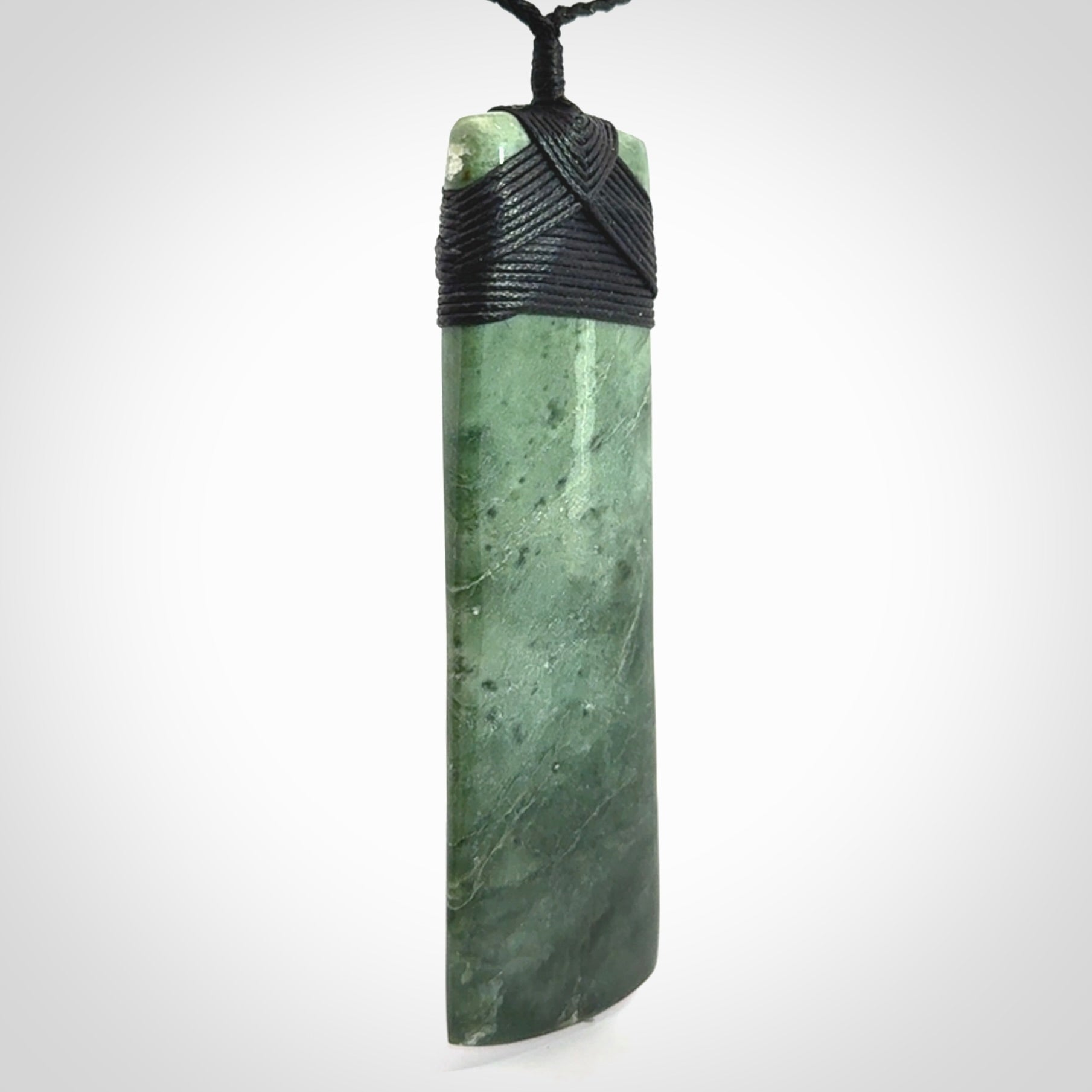 A large and beautiful hand carved toki pendant. This piece is carved from New Zealand jade by NZ Pacific. This is a wonderful large toki bound with a hand-plaited black cord and a traditional black lashing. A beautiful, traditional toki for sale online.