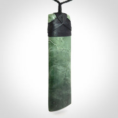 A large and beautiful hand carved toki pendant. This piece is carved from New Zealand jade by NZ Pacific. This is a wonderful large toki bound with a hand-plaited black cord and a traditional black lashing. A beautiful, traditional toki for sale online.