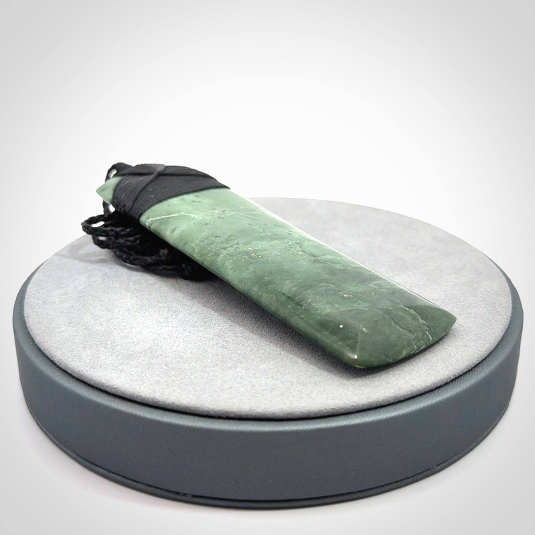A large and beautiful hand carved toki pendant. This piece is carved from New Zealand jade by NZ Pacific. This is a wonderful large toki bound with a hand-plaited black cord and a traditional black lashing. A beautiful, traditional toki for sale online.