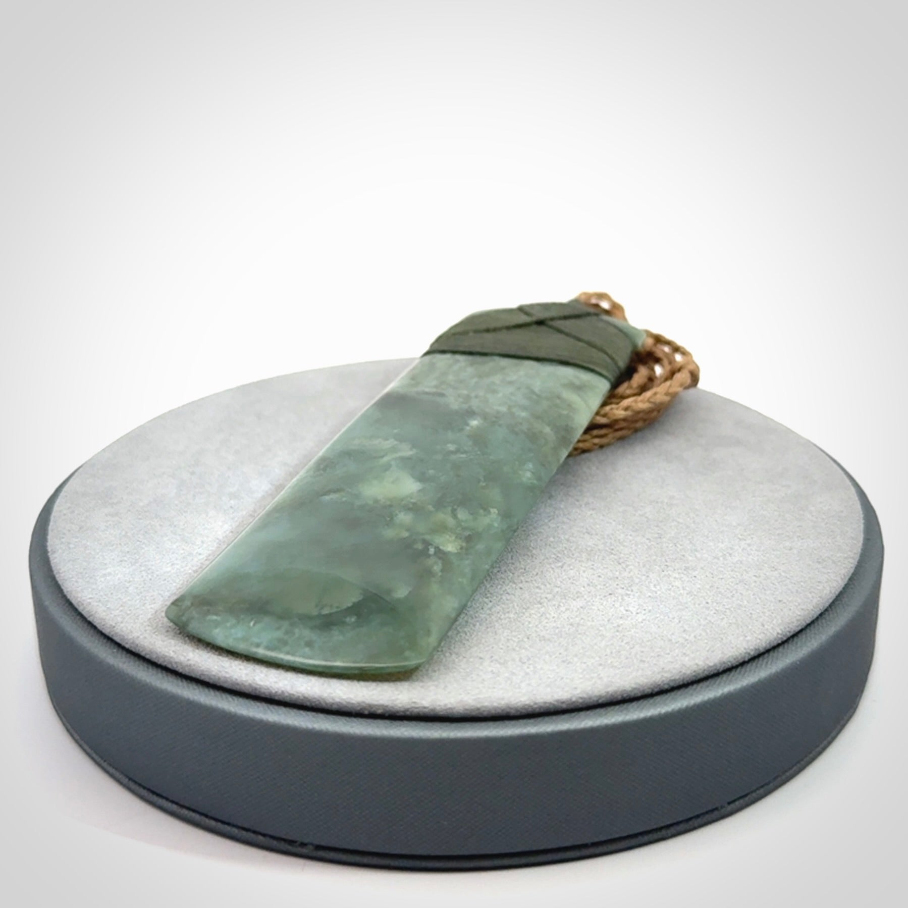 A large and beautiful hand carved toki pendant. This piece is carved from New Zealand jade by NZ Pacific. This is a wonderful large toki bound with a tan cord and a traditional sage green lashing. A beautiful, traditional toki for sale online.