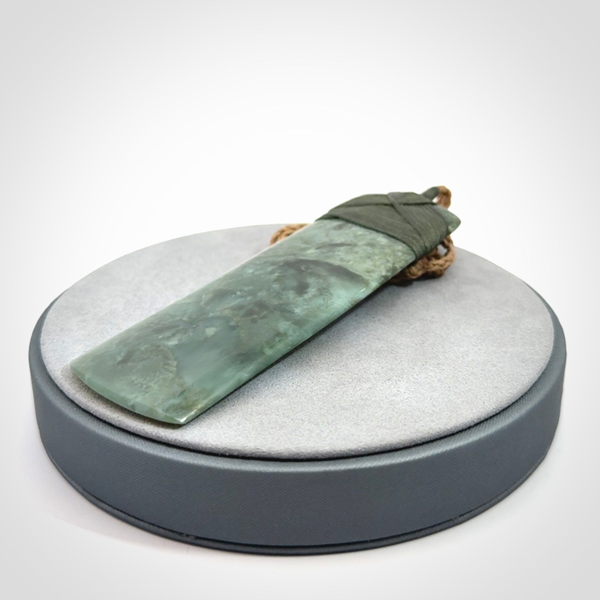 A large and beautiful hand carved toki pendant. This piece is carved from New Zealand jade by NZ Pacific. This is a wonderful large toki bound with a tan cord and a traditional sage green lashing. A beautiful, traditional toki for sale online.