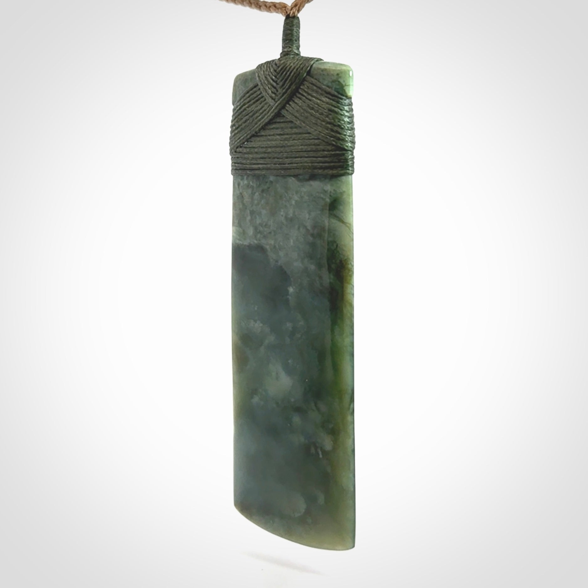 A large and beautiful hand carved toki pendant. This piece is carved from New Zealand jade by NZ Pacific. This is a wonderful large toki bound with a tan cord and a traditional sage green lashing. A beautiful, traditional toki for sale online.