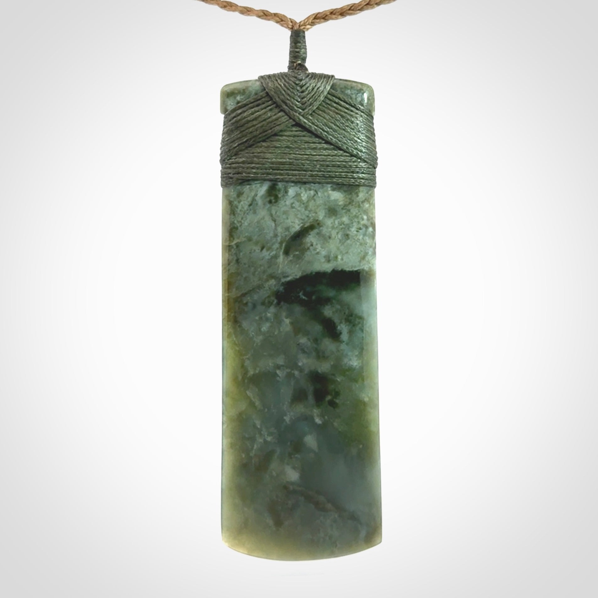 A large and beautiful hand carved toki pendant. This piece is carved from New Zealand jade by NZ Pacific. This is a wonderful large toki bound with a tan cord and a traditional sage green lashing. A beautiful, traditional toki for sale online.