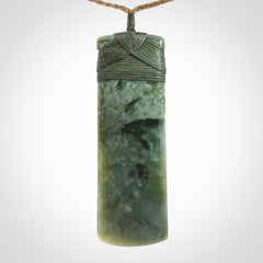 A large and beautiful hand carved toki pendant. This piece is carved from New Zealand jade by NZ Pacific. This is a wonderful large toki bound with a tan cord and a traditional sage green lashing. A beautiful, traditional toki for sale online.