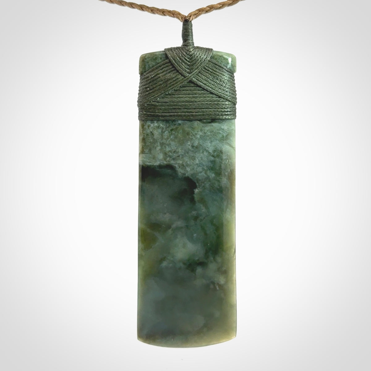 A large and beautiful hand carved toki pendant. This piece is carved from New Zealand jade by NZ Pacific. This is a wonderful large toki bound with a tan cord and a traditional sage green lashing. A beautiful, traditional toki for sale online.