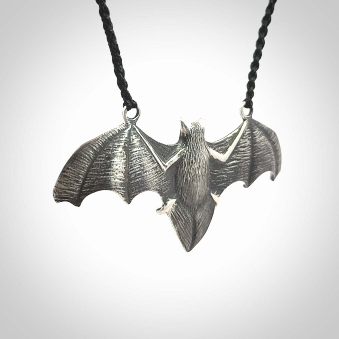 This is a hand carved bat pendant. It is made from New Zealand Jade and Sterling Silver. This is a medium sized necklace and is a very unique, one only, pendant that is a collectors piece. Provided with black adjustable cord.