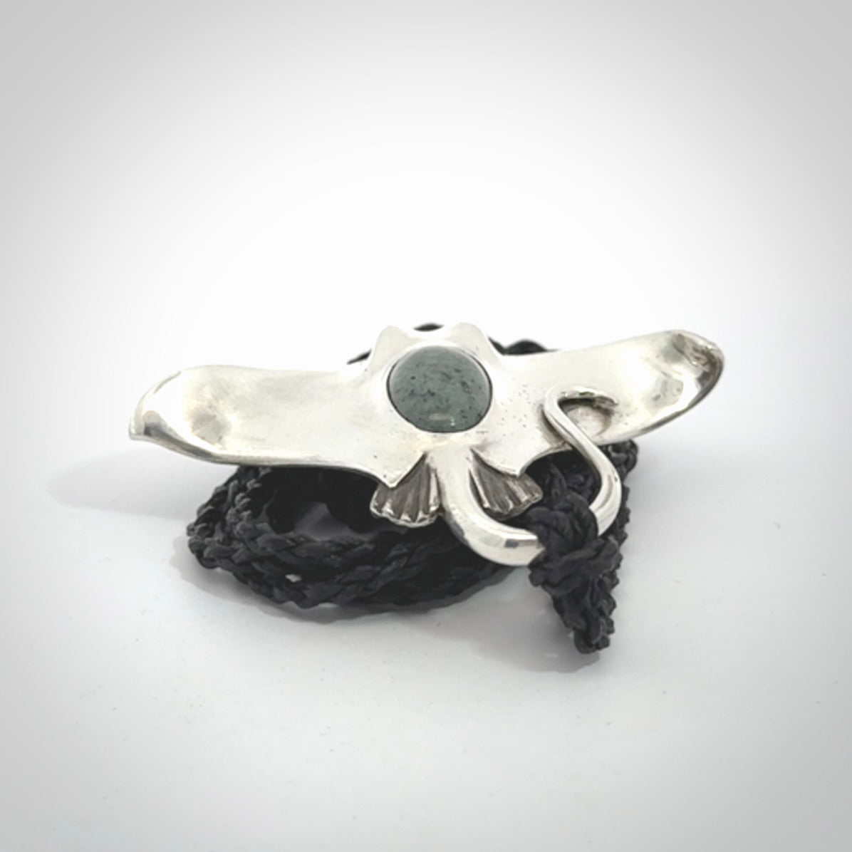 This is a hand carved Sterling Silver Eagle Ray pendant with New Zealand Jade insert. This is a medium sized necklace and is provided with an adjustable black cord.