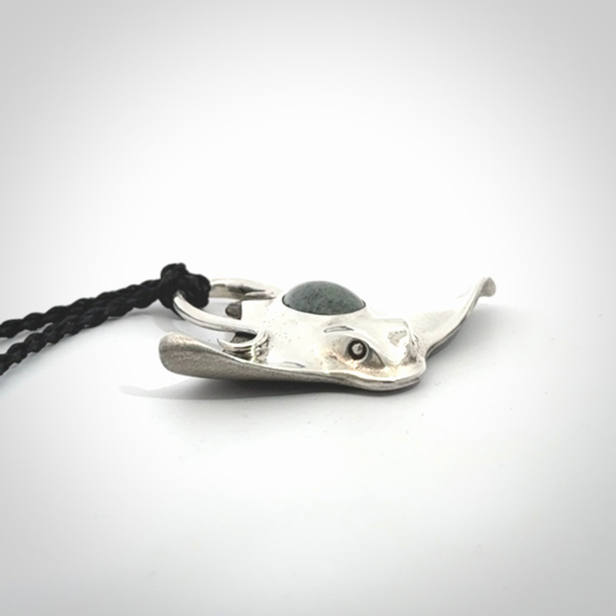 This is a hand carved Sterling Silver Eagle Ray pendant with New Zealand Jade insert. This is a medium sized necklace and is provided with an adjustable black cord.