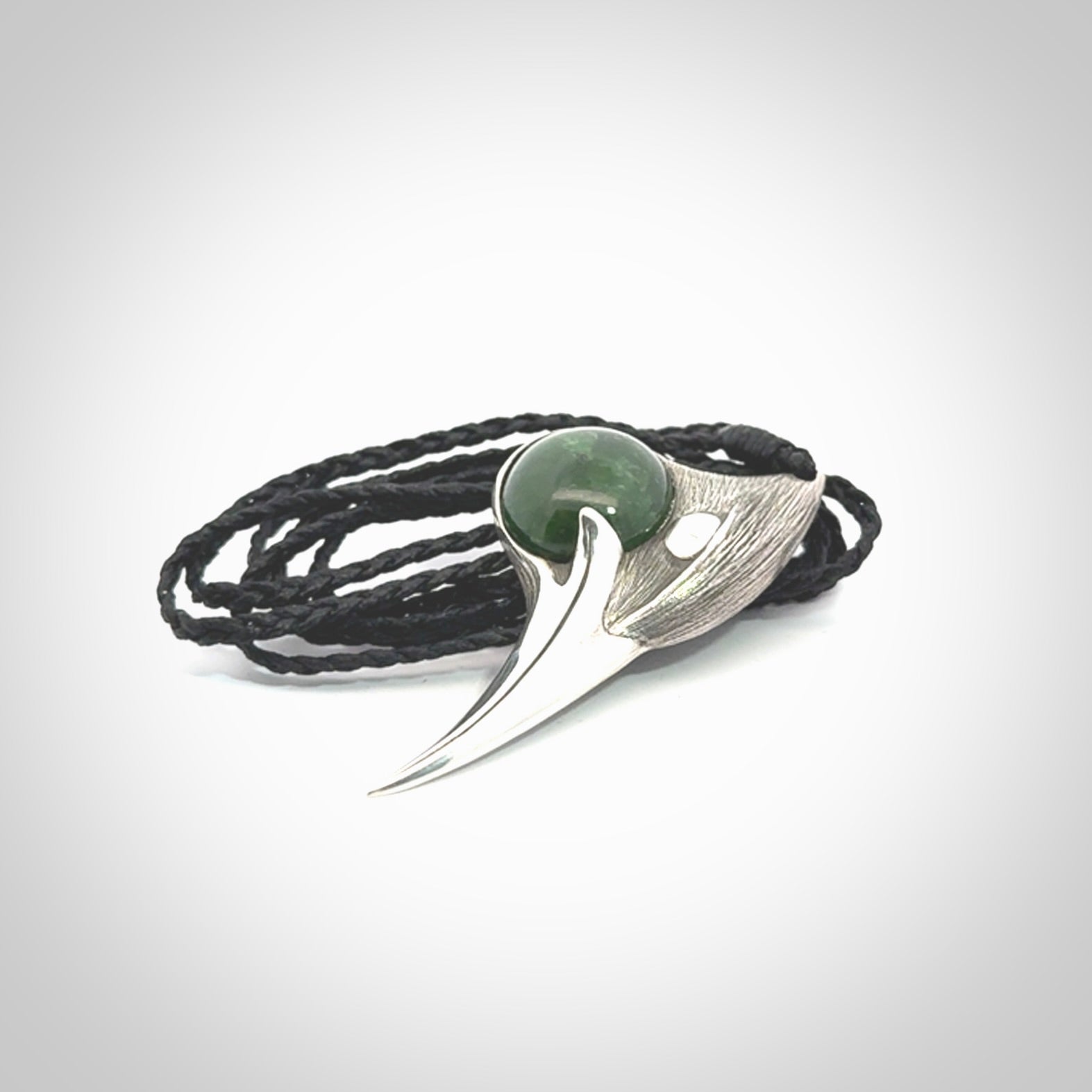 This is a hand carved Sterling Silver Huia bird pendant with New Zealand Jade insert. This is a medium sized necklace and is provided with an adjustable black cord.